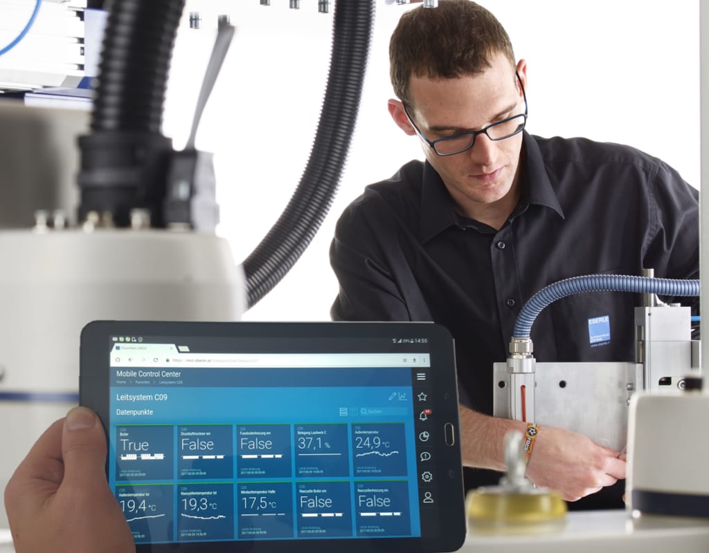 Tablet mit dem Mobile Control Center von control zeigt Live-Prozessdaten eines Leitsystems, im Hintergrund ein Techniker an der Anlage.